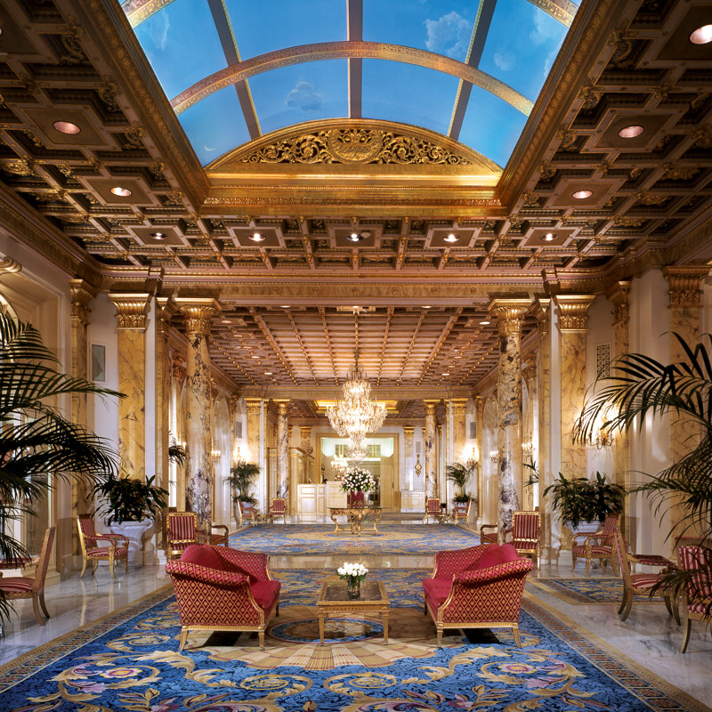 Fairmont Copley Hotel lobby with red couches, blue rug, and gold accents along the wall.