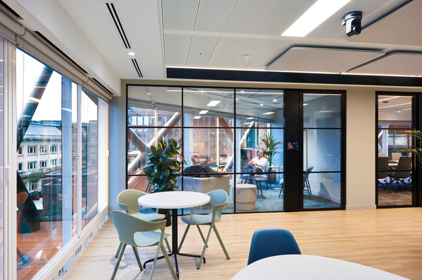 A spacious section of Structure Tone London's office with ample seating and a wide window offering natural light.