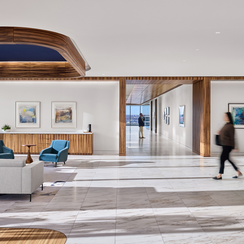 A modern office lobby featuring a reception desk and seating area with chairs.