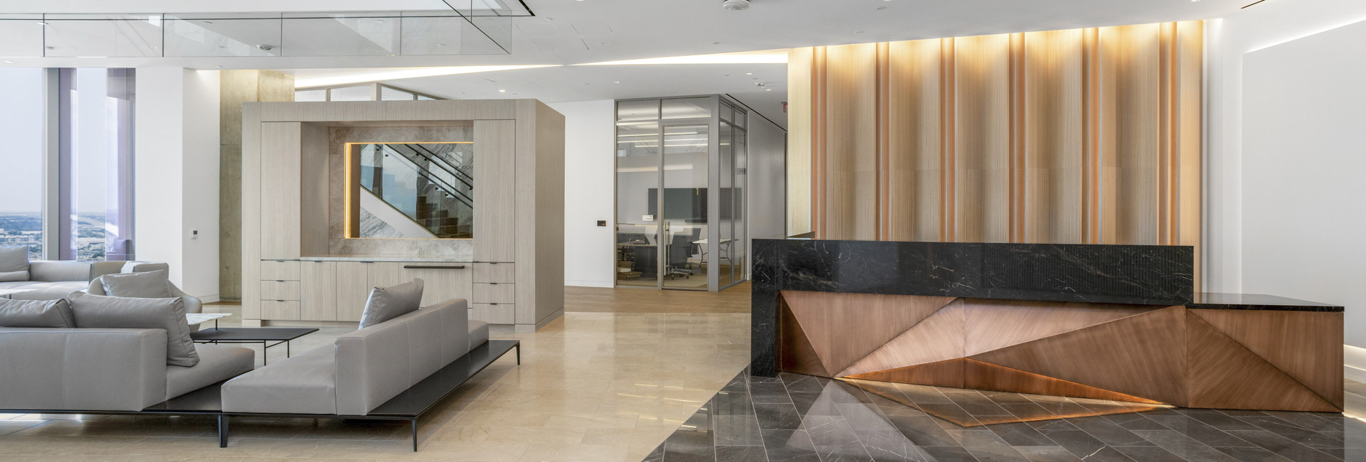 A contemporary office featuring a sleek reception desk and comfortable couches for visitors and clients.