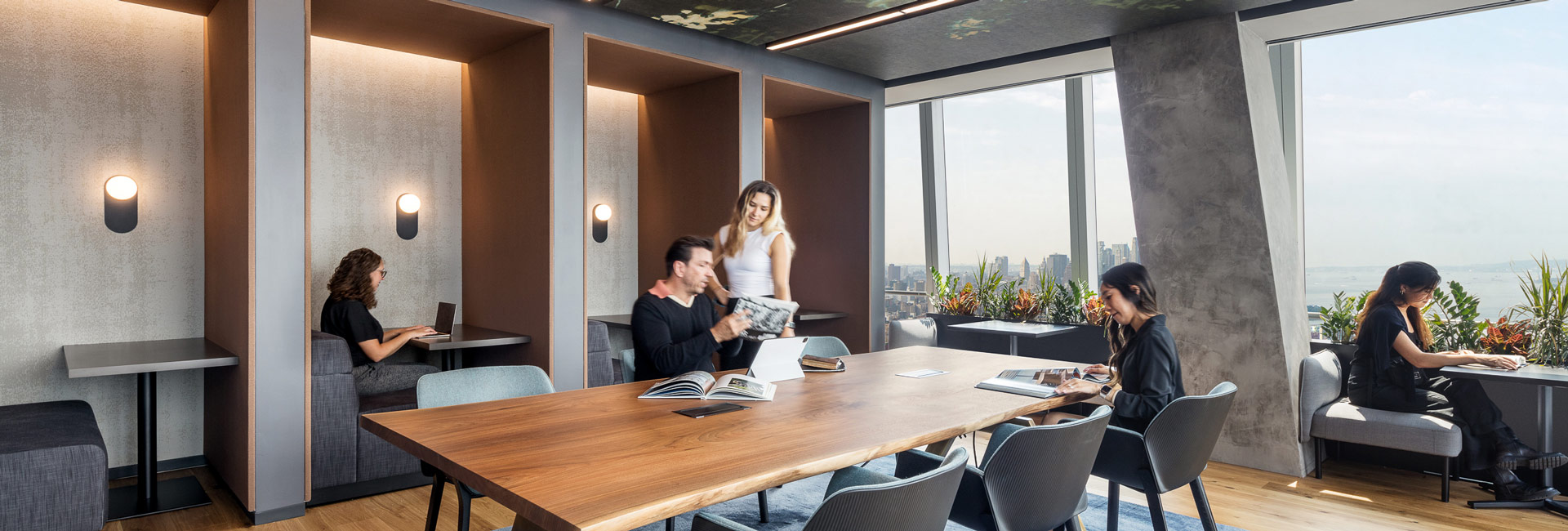 Employees sitting and standing around a large wooden desk.