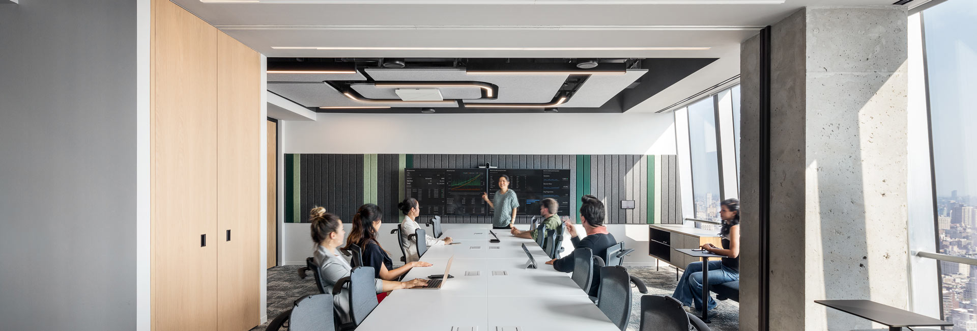 A group of coworkers having a meeting in a large conference room with a long table and chairs.