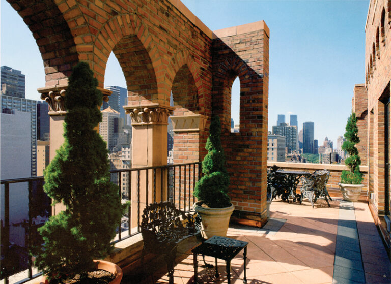 Outdoor terrace with brick feature wall and tables overlooking the New York skyline.