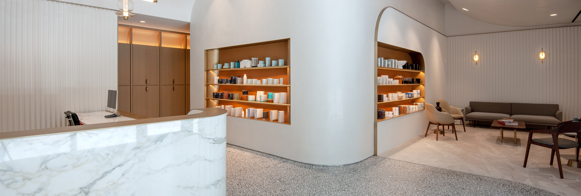 Reception area with seating and built in book shelf with skincare products.