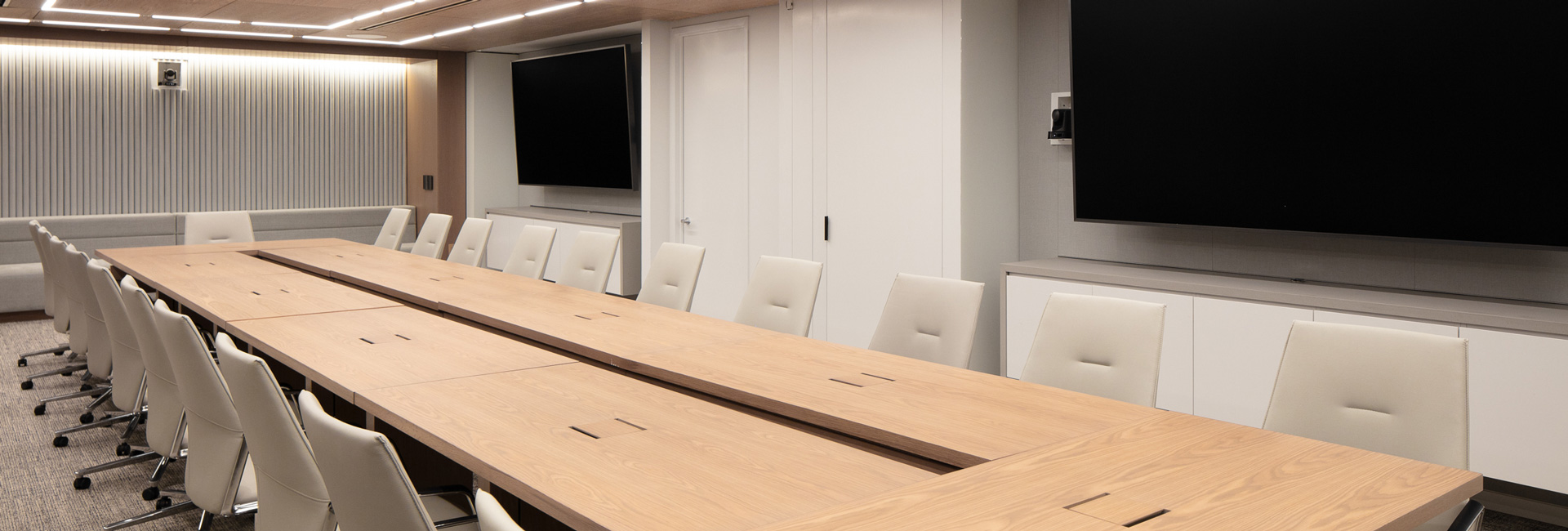 A large conference room with a long wooden table with several white chairs