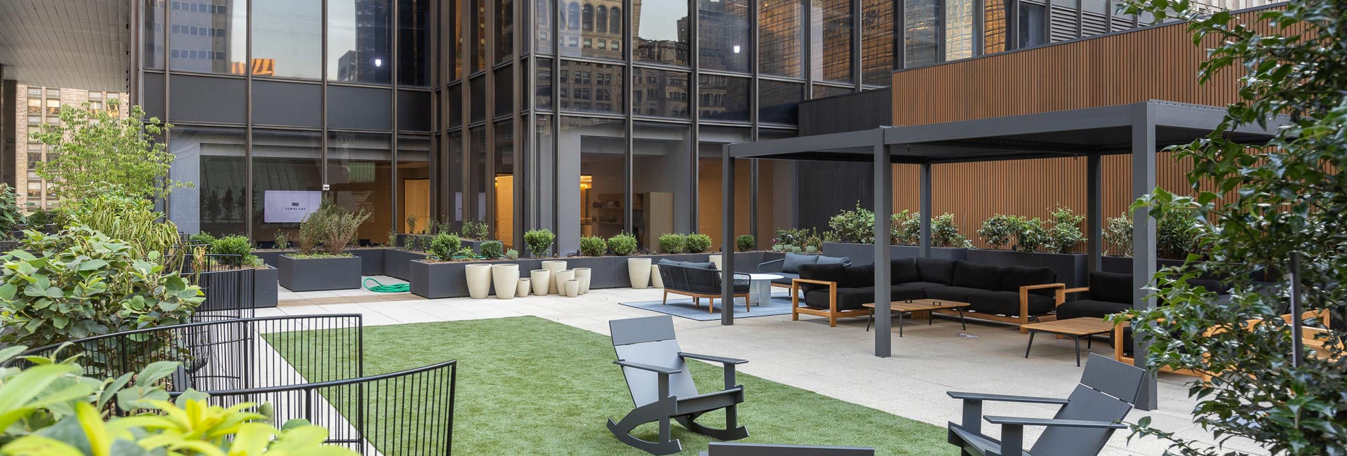 An outdoor patio area with tables and chairs and an open green area