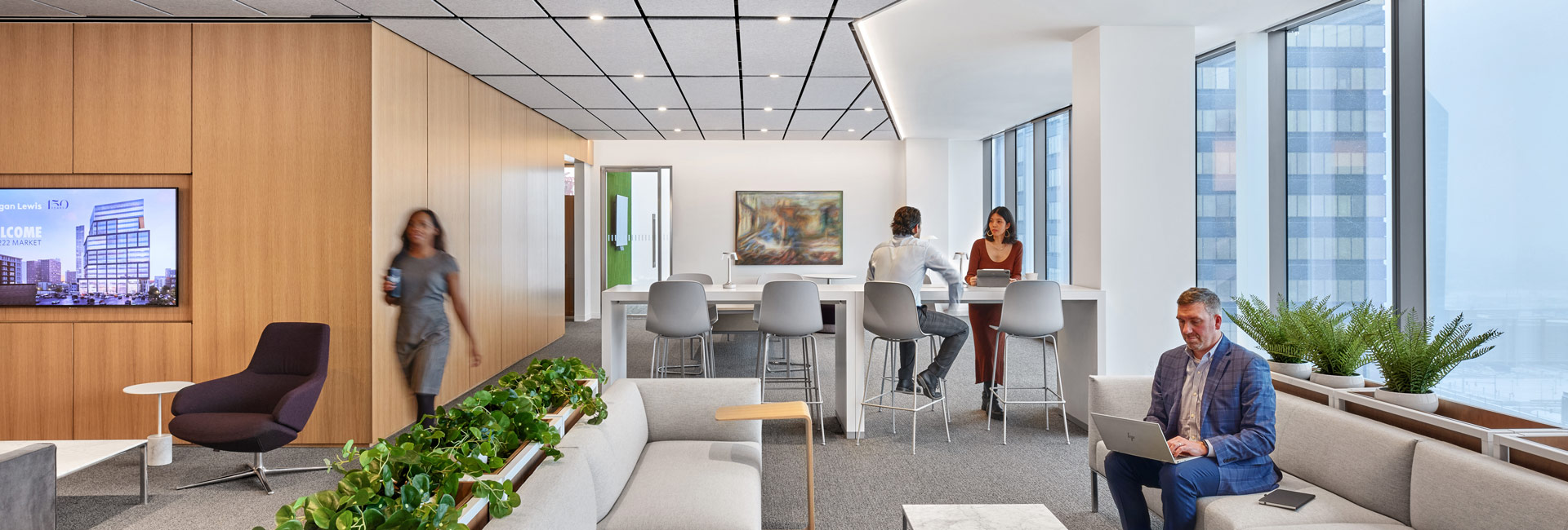 A modern office interior featuring desks, chairs, and large windows allowing natural light to illuminate the space.