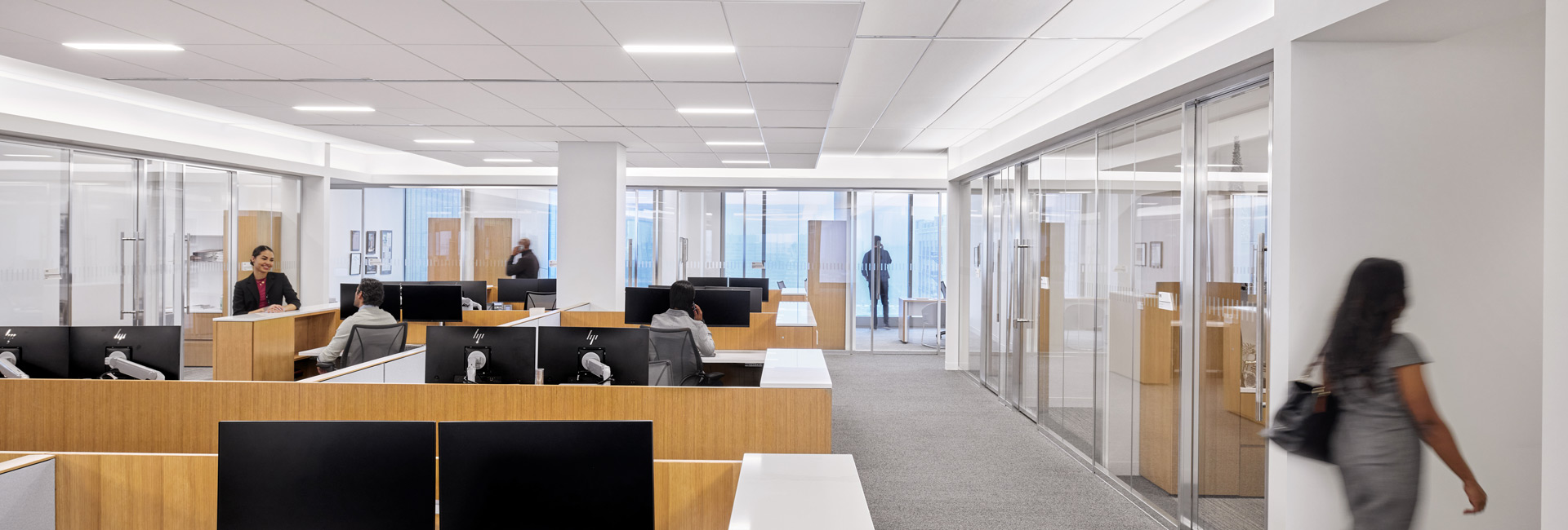 A spacious open office featuring desks and employees engaged in various activities throughout the workspace.