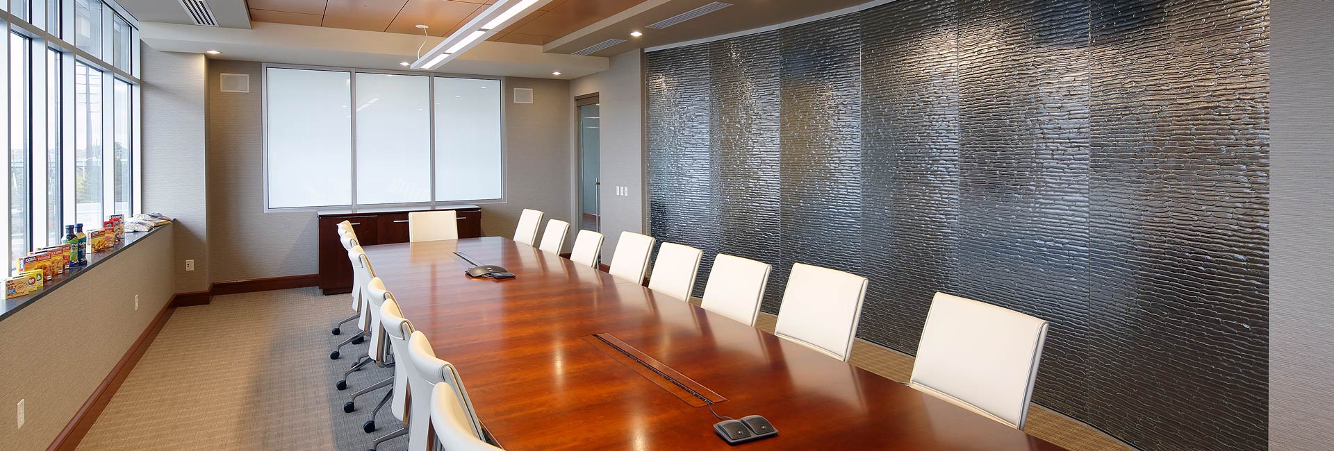 A spacious conference room featuring a long table surrounded by several chairs, ready for a meeting or discussion.