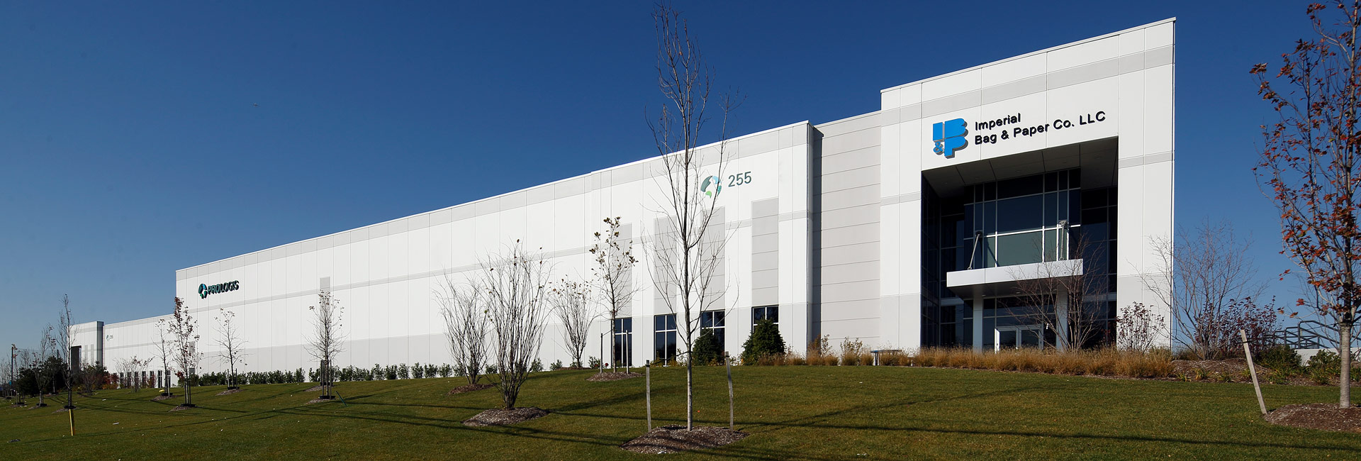 A large white warehouse building stands prominently against a lush green lawn, creating a serene and inviting atmosphere.