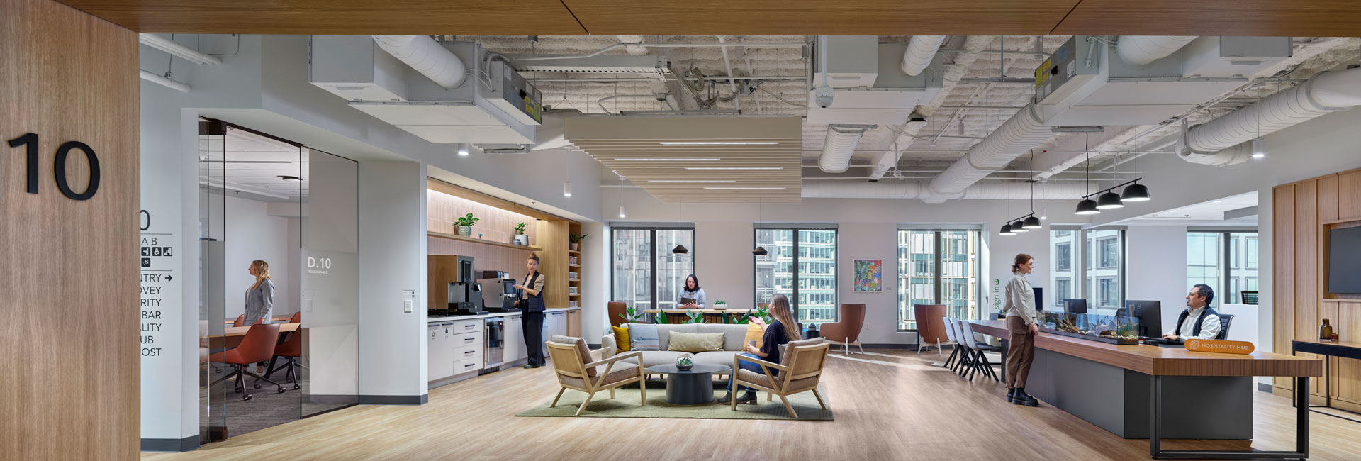 A spacious open office featuring wooden floors and large windows, allowing ample natural light to illuminate the workspace.