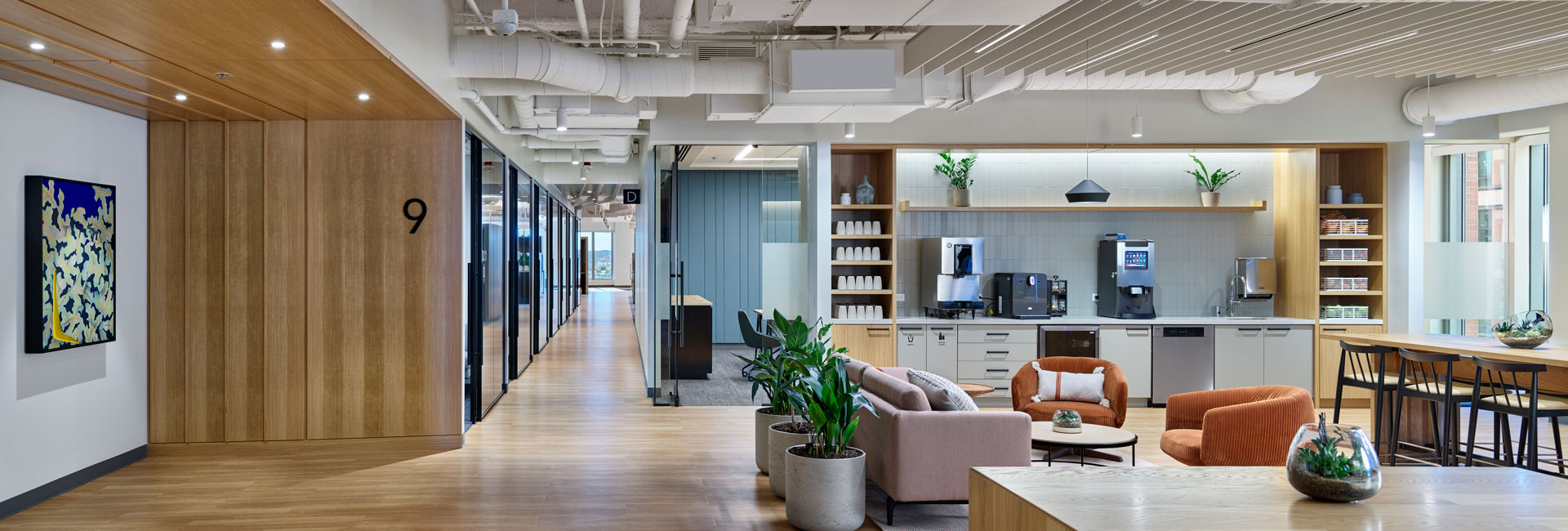 A modern office featuring a kitchen, dining area, and bar, designed for both work and relaxation.