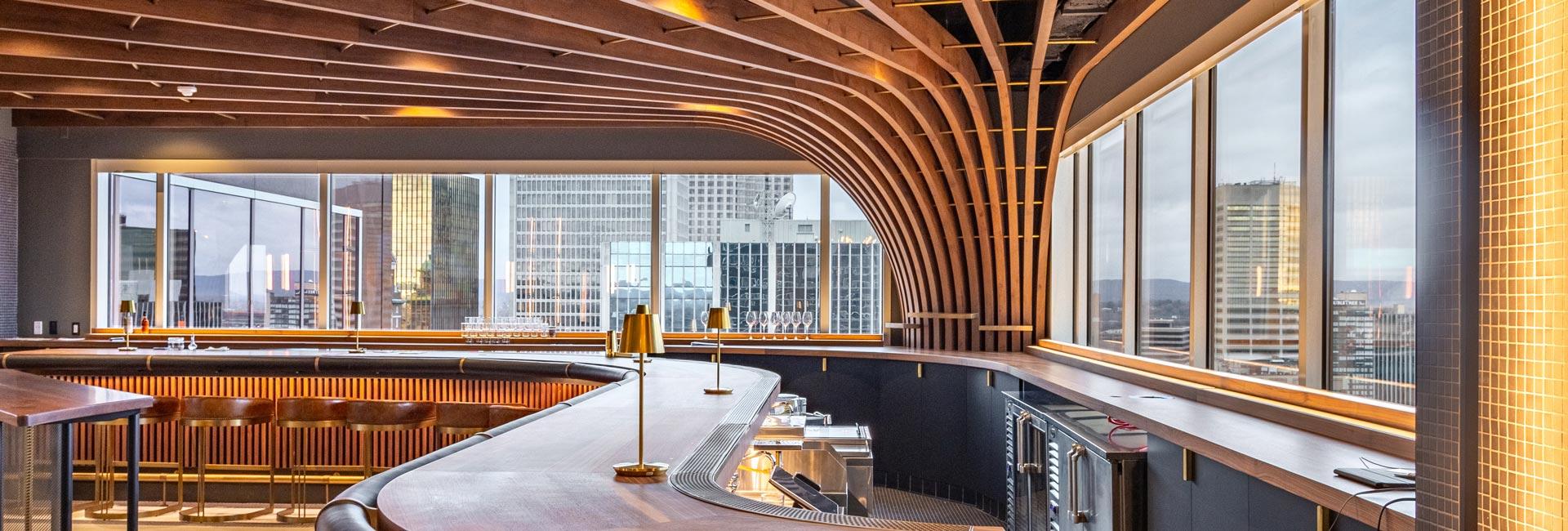 A rooftop bar featuring a stylish curved wall, offering a unique architectural design and panoramic views of the city.