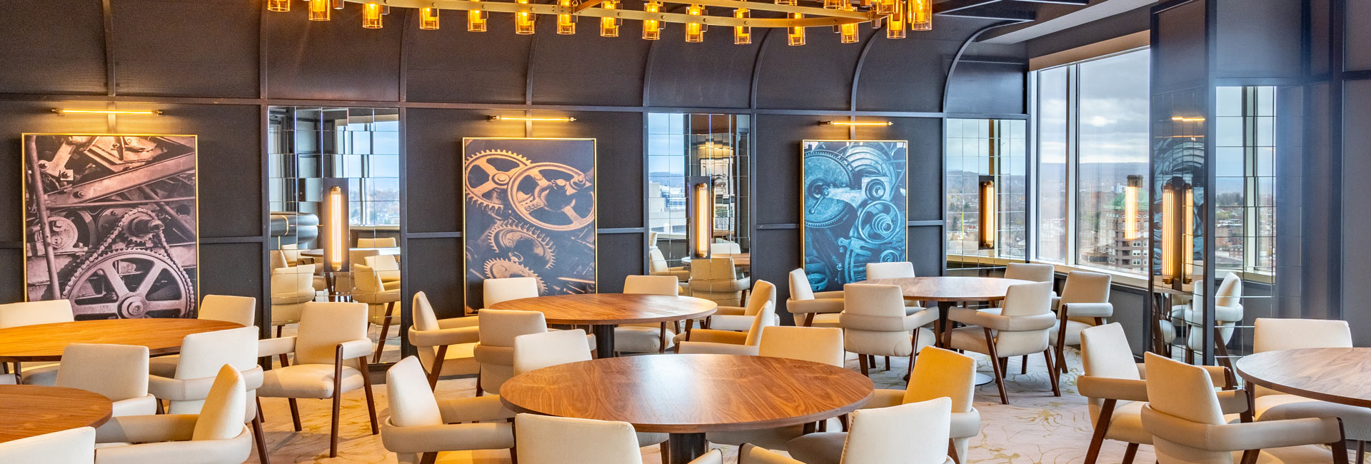 A restaurant interior featuring tables and chairs arranged near a large window, inviting natural light inside.