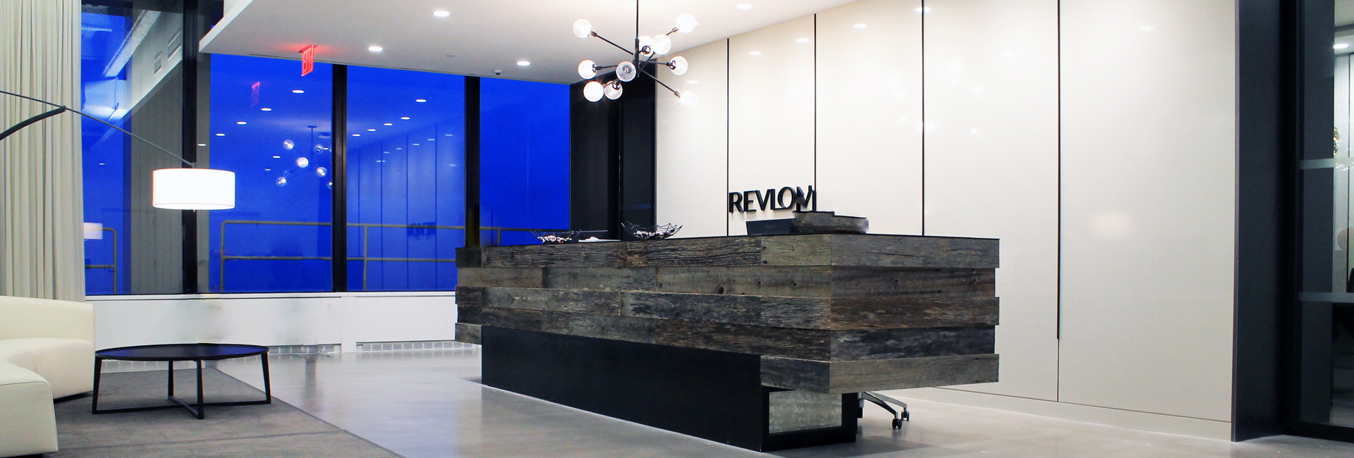 A modern office interior showcasing a stylish reception desk and a large window that enhances the room's brightness.