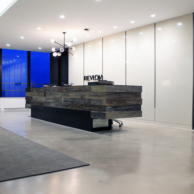 A modern office interior showcasing a stylish reception desk and a large window that enhances the room's brightness.