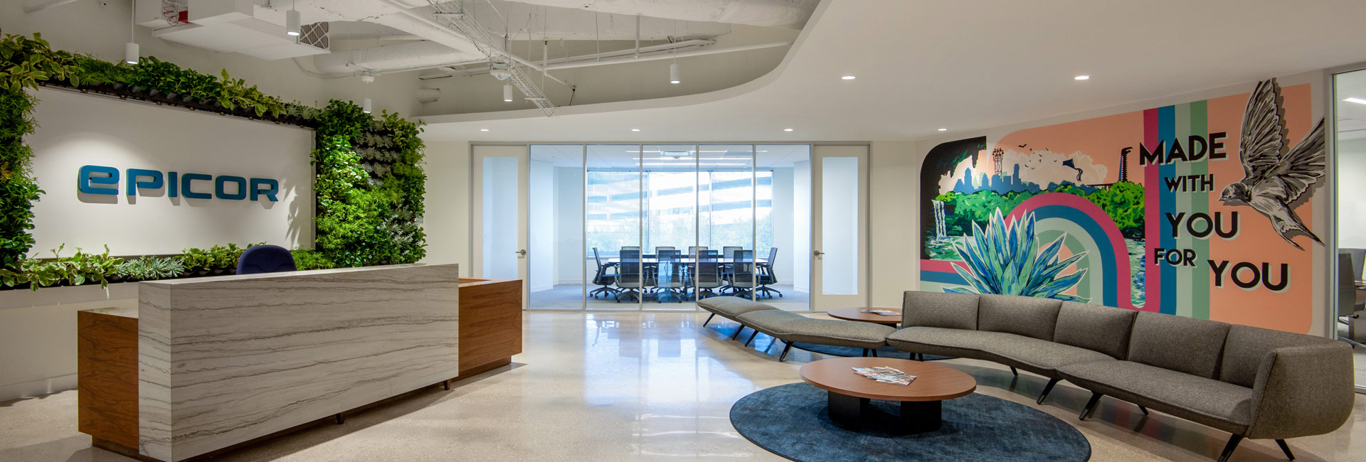 A spacious office lobby showcasing a large wall adorned with various lush green plants, enhancing the inviting atmosphere.