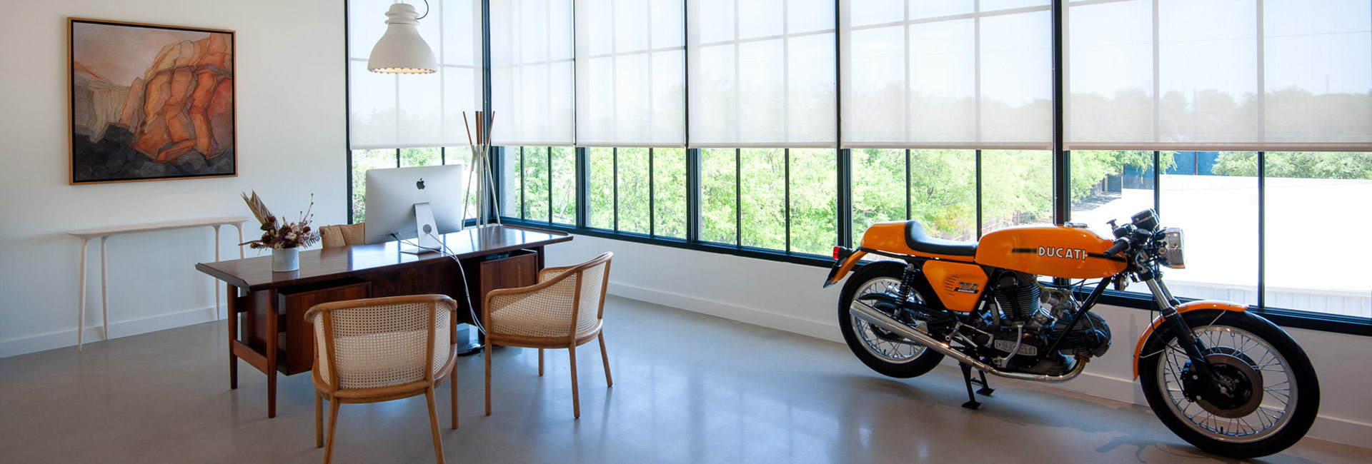 A motorcycle parked in a room featuring a desk and a chair, creating a unique blend of workspace and leisure.