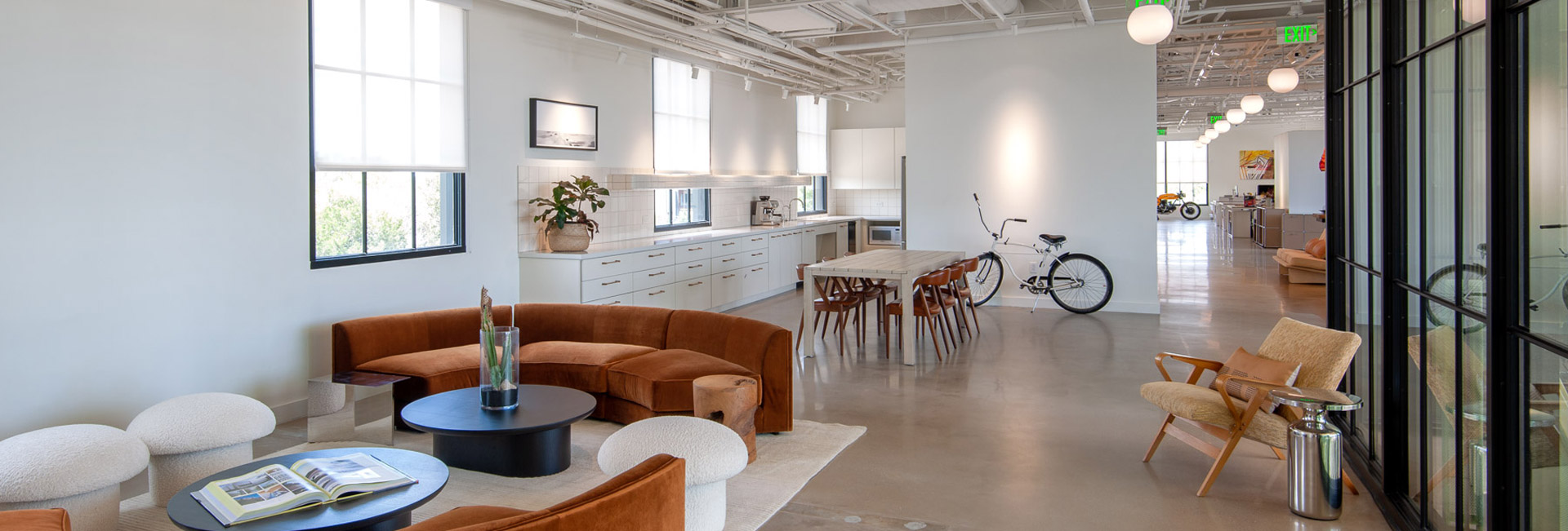 A spacious office featuring an open layout with natural light and a bicycle positioned prominently in the foreground.