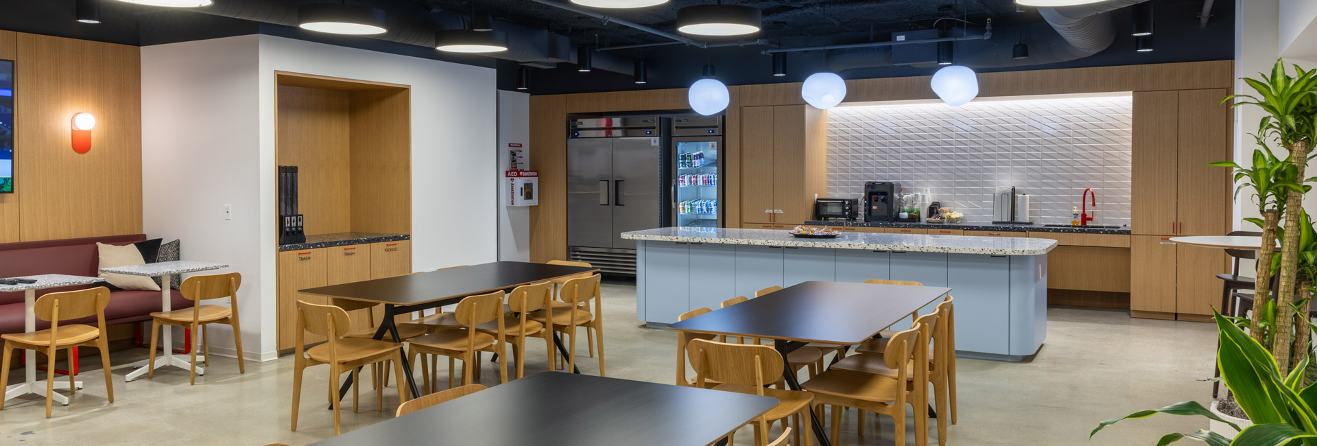 A modern office featuring a spacious kitchen and a large dining table for collaborative meetings and meals.