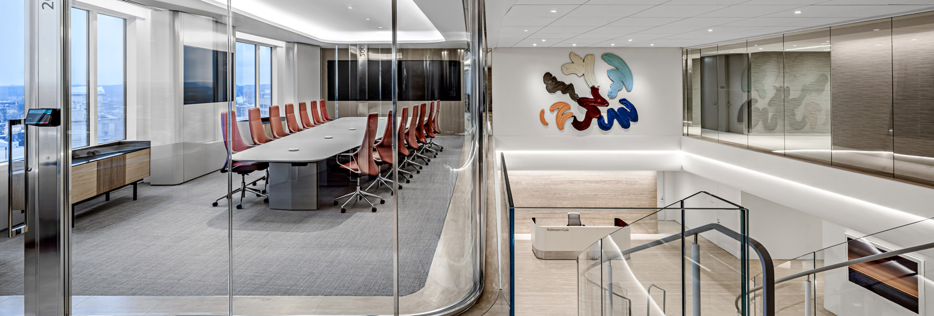 A modern conference room featuring a glass wall and a large, colorful painting on the adjacent wall.