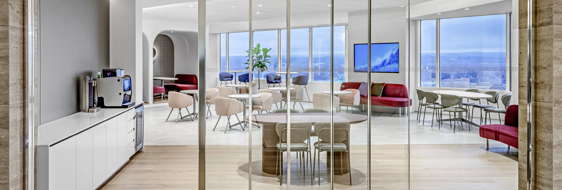 Interior of a glass-walled room with a spacious table and several chairs, suitable for collaborative work.