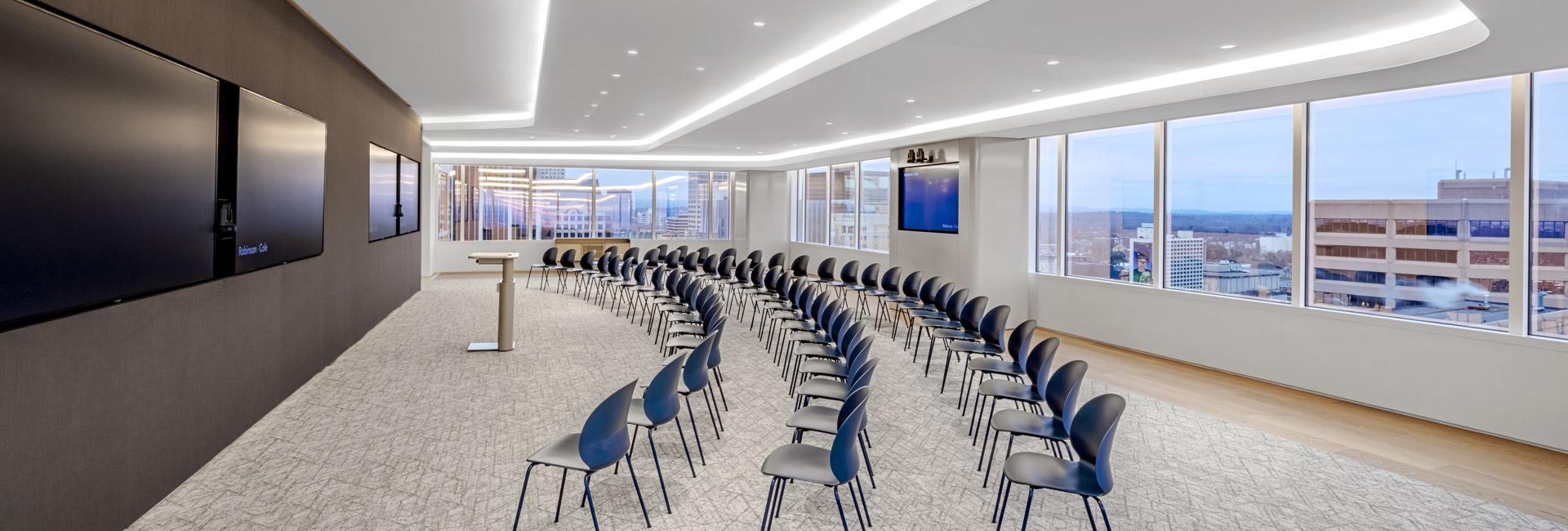 A conference room featuring several chairs arranged around a large screen for presentations or meetings.