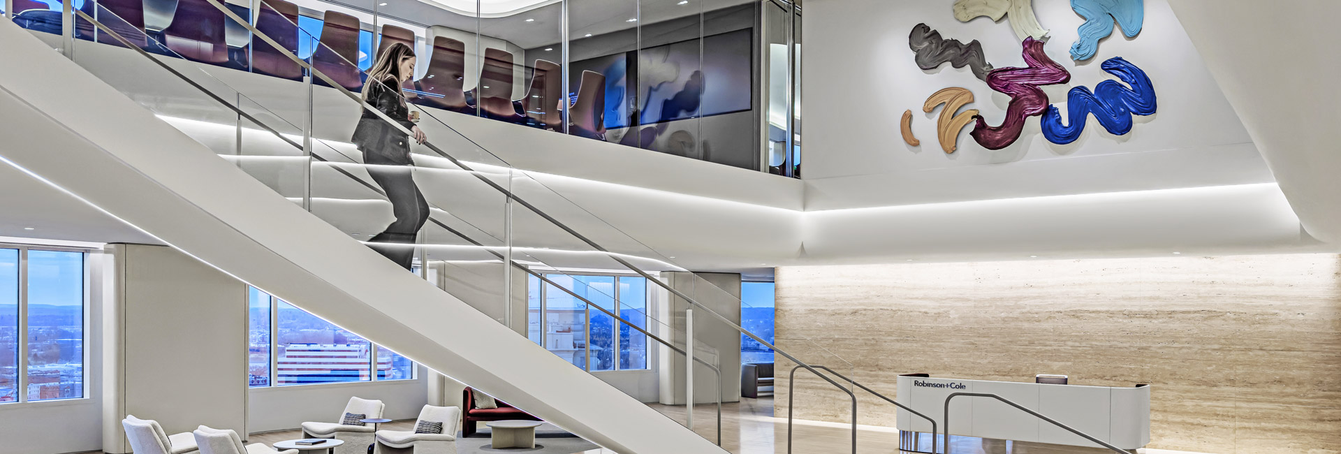A modern office featuring a staircase and a large abstract painting on the wall, creating a vibrant work environment.
