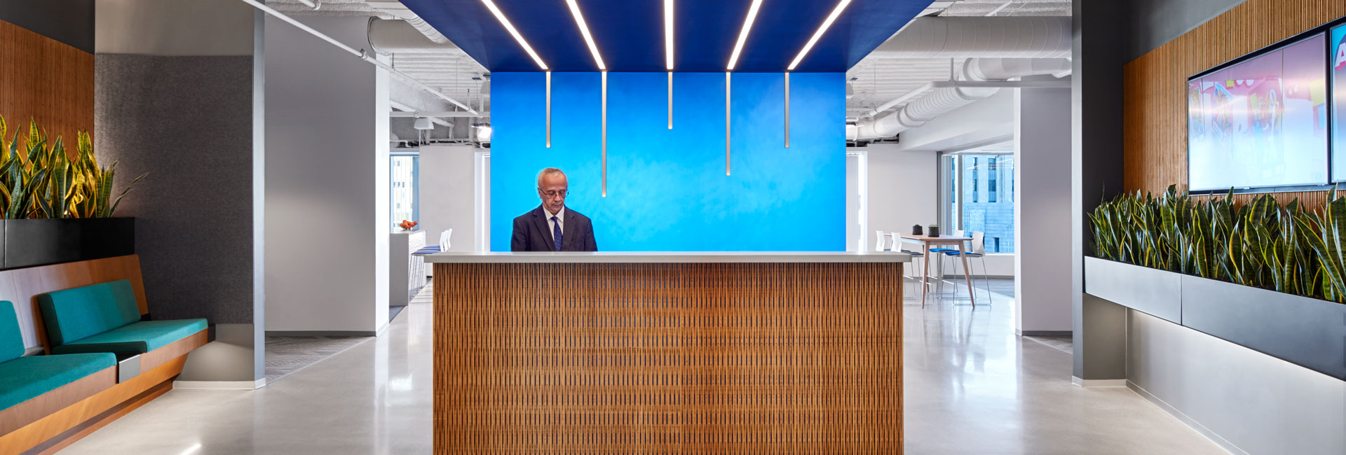 A modern office lobby featuring a large blue wall with a professional reception area in front.