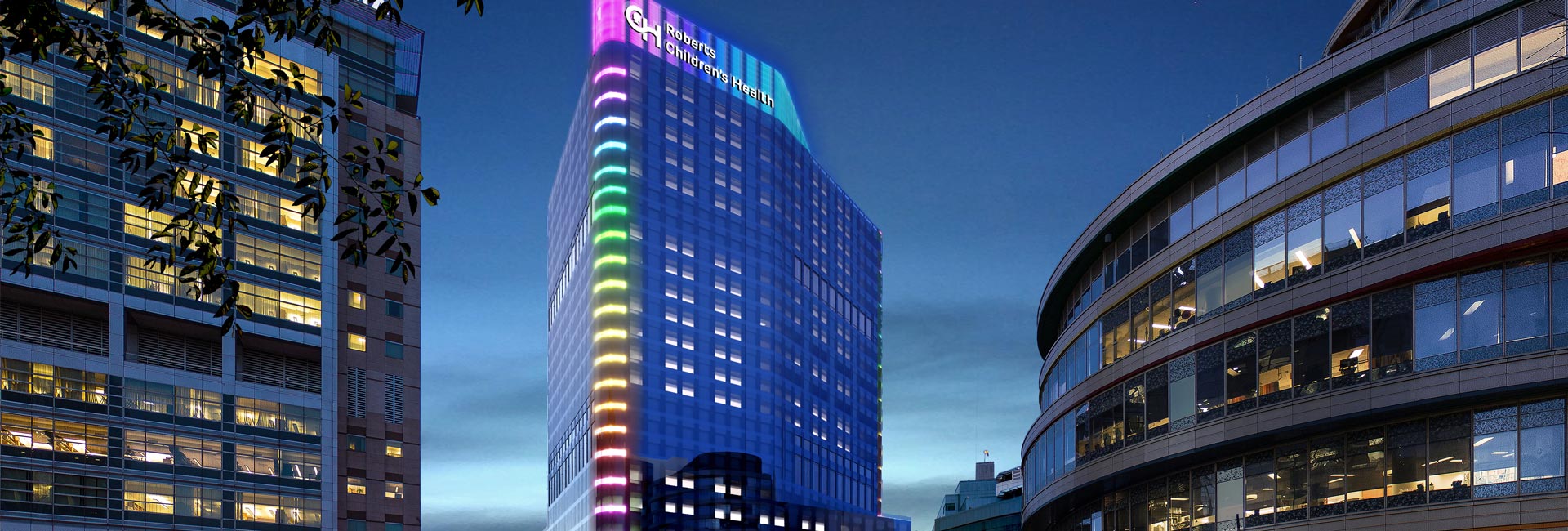 A tall building illuminated by vibrant rainbow-colored lights against a night sky.
