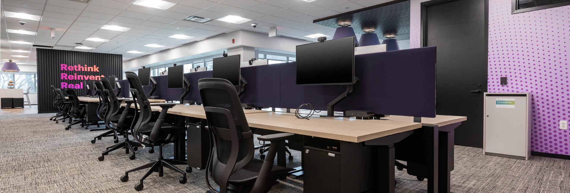 A spacious Accenture office featuring purple walls and sleek black chairs arranged for a modern work environment.