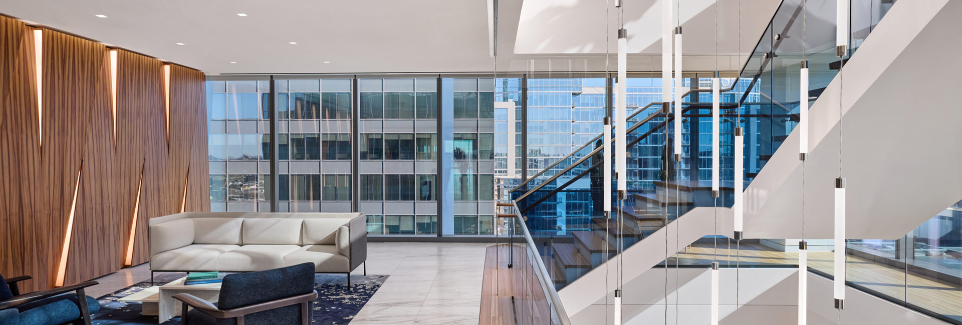 A modern office lobby featuring glass walls and a sleek staircase, creating an open and inviting atmosphere.