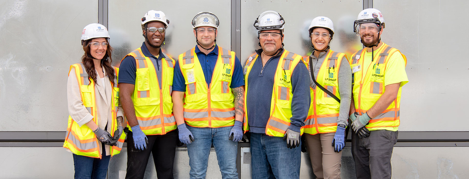 workers with yellow vest, hard hat, gloves lined up for a picture smiling