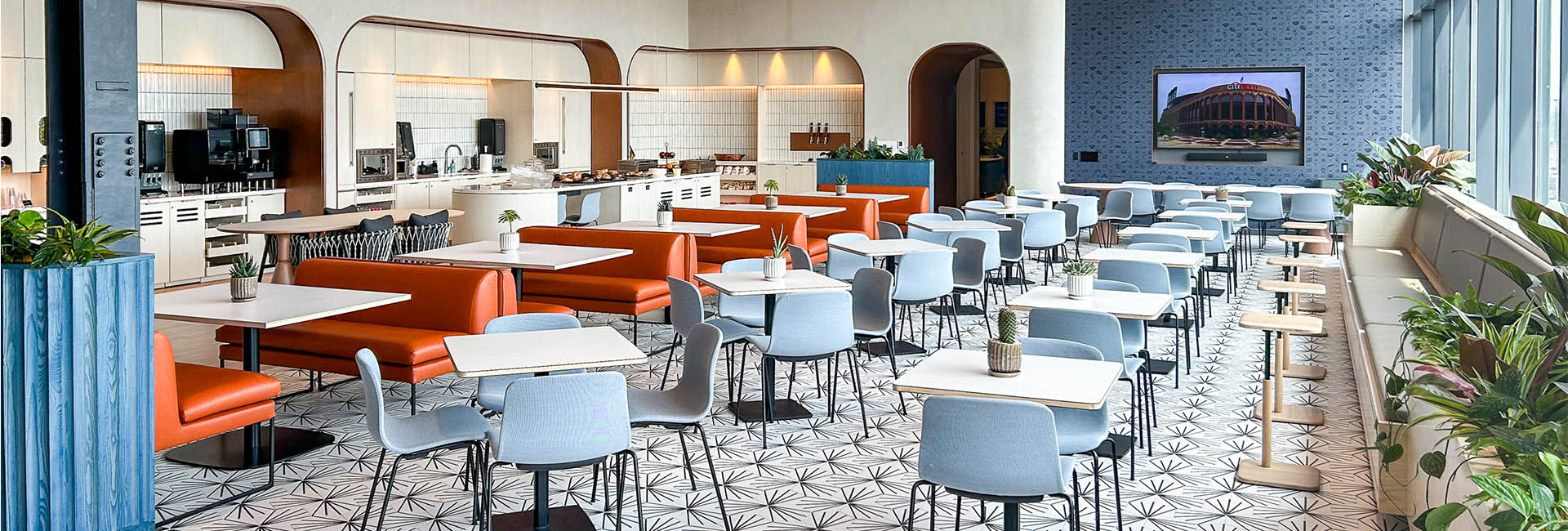 Citi field The Hub: A vibrant blue and orange accent restaurant interior featuring neatly arranged tables and chairs for dining.