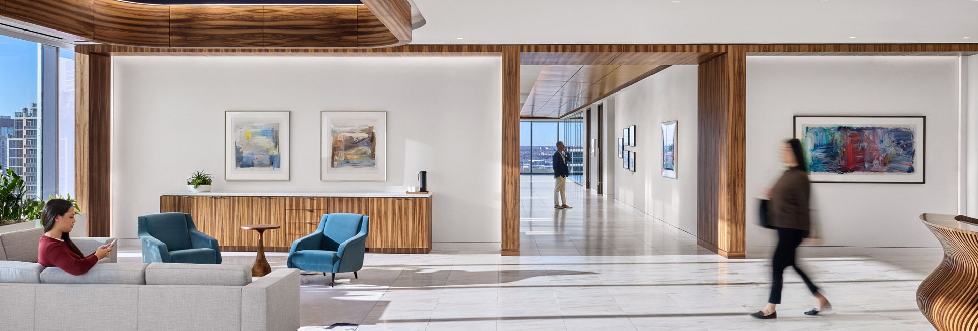 A modern office lobby featuring a reception desk and seating area with chairs.