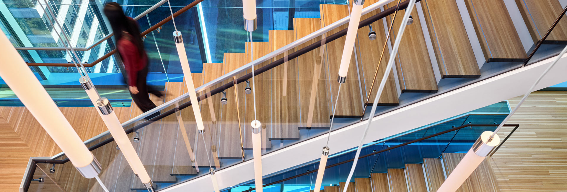 A person descends a staircase inside a building, showcasing the architectural design and interior space.