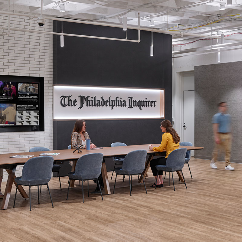The interior of The Philadelphia Inquirer with a long table wooden floors and glowing logo with black typeface letters built by Structure Tone PA