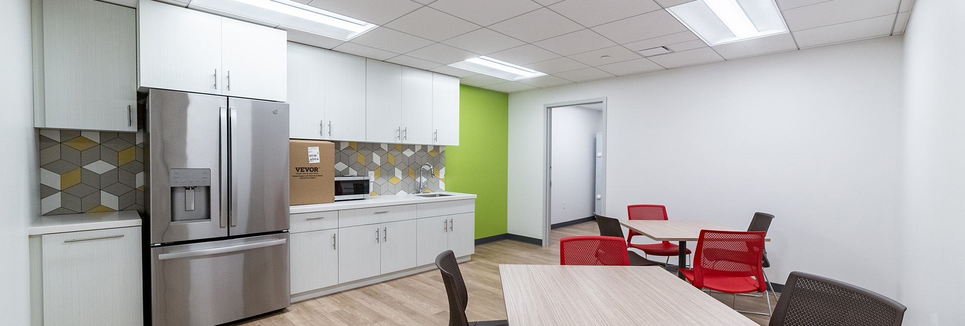 A break room with stainless steel appliances and green wall accent at Temple Dental done by Structure Tone PA