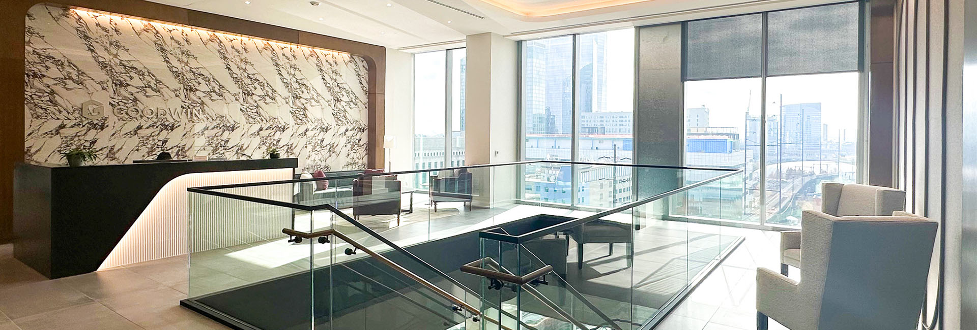 Goodwin Proctor front desk area with marble wall logo and large stair case in center with row of windows built by Structure Tone