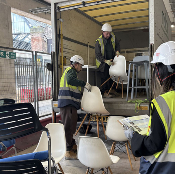 people in safety gear putting furniture on a truck