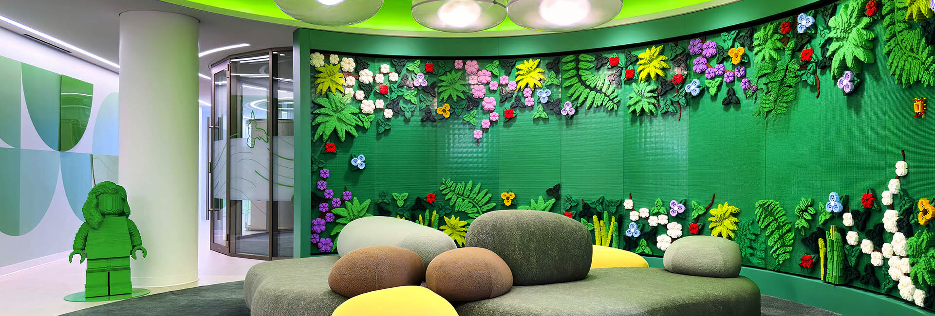 Lego HQ Boston image of a lounge area with a colorful LEGO Flower wall with green background and rock seating area built by Structure Tone Boston