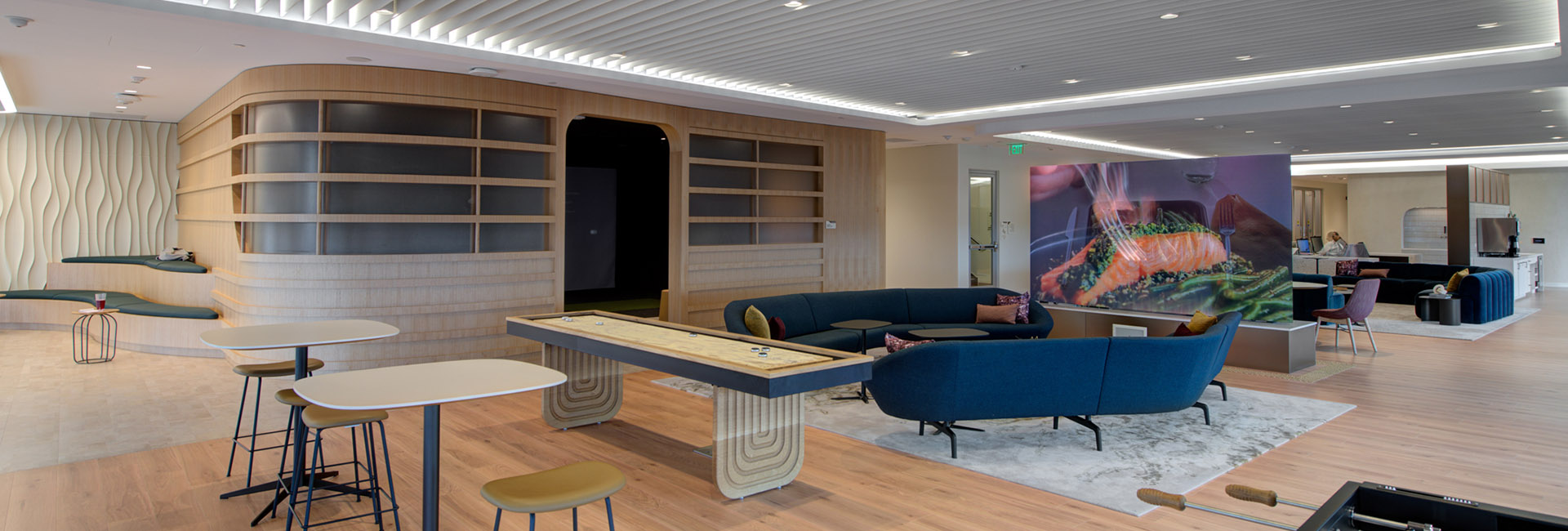 TIAA Corporate Center common area with accent walls, cool blue couches, various game tables built by Structure Tone Southwest.