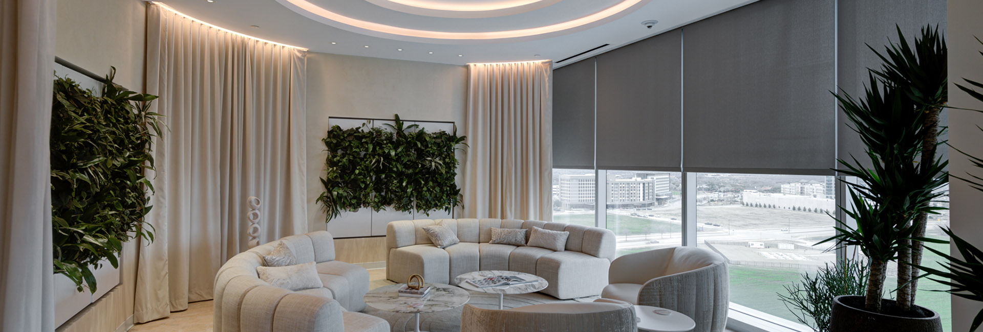 Elegant seating area at the TIAA Corporate Center with oval couch area and round marble tables, faux foliage wall accents and large windows built by Structure Tone Southwest