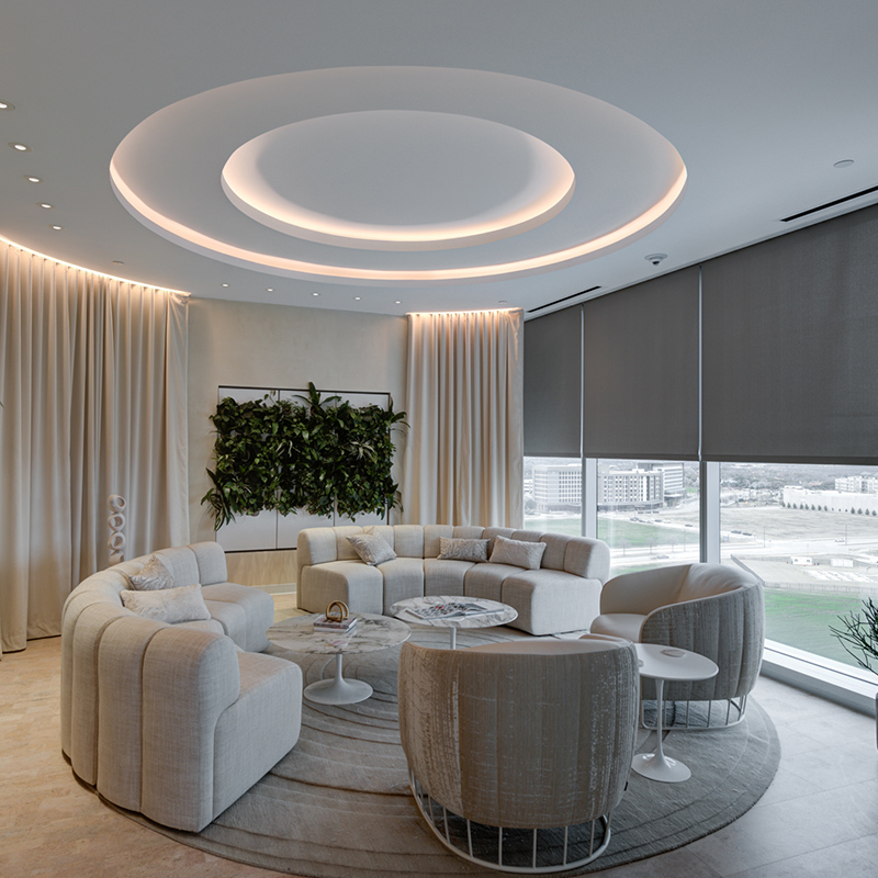 Elegant seating area at the TIAA Corporate Center with oval couch area and round marble tables, faux foliage wall accents and large windows built by Structure Tone Southwest