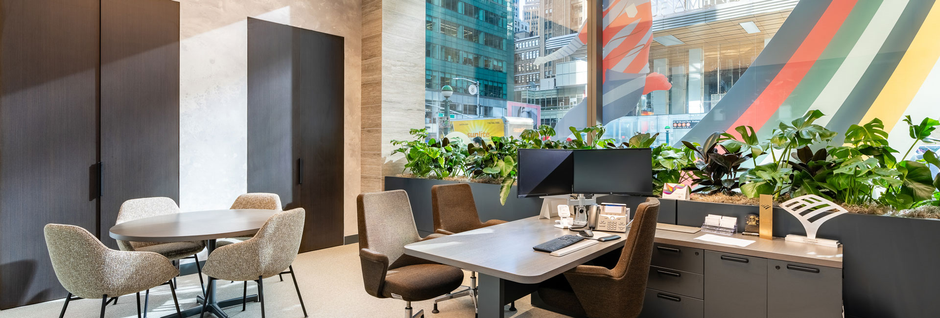 A modern office featuring a desk, chairs, and decorative plants, creating a professional and inviting workspace.