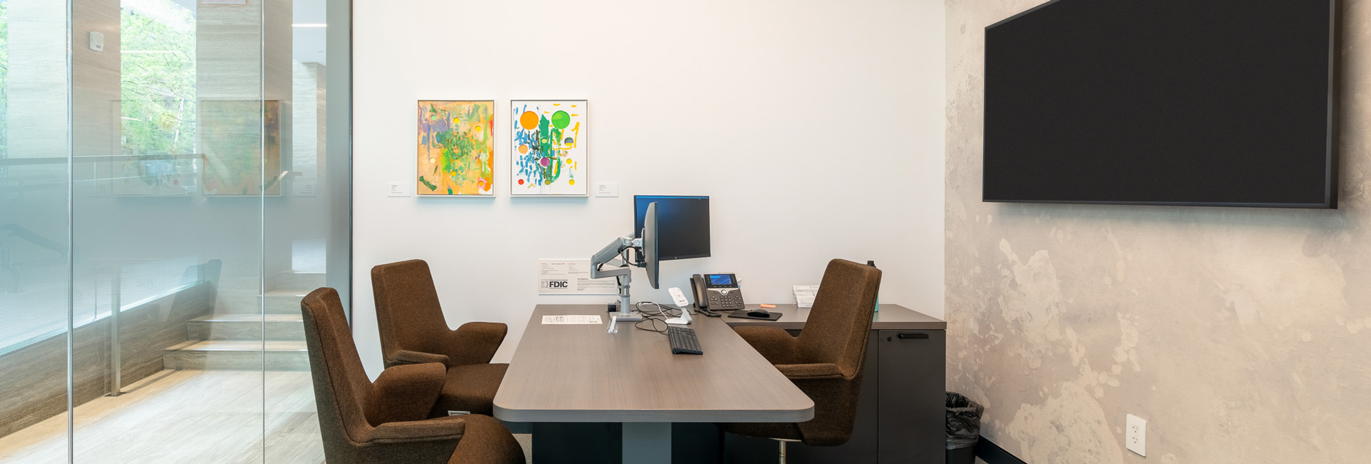 A modern office featuring a large desk surrounded by several chairs, designed for a professional workspace.