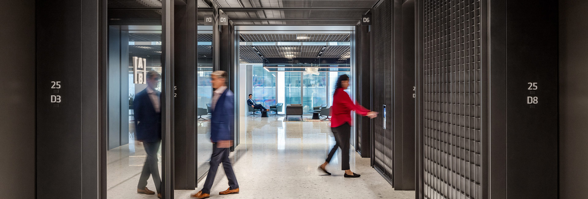 Two employees waiting in a open lobby area for the elevator