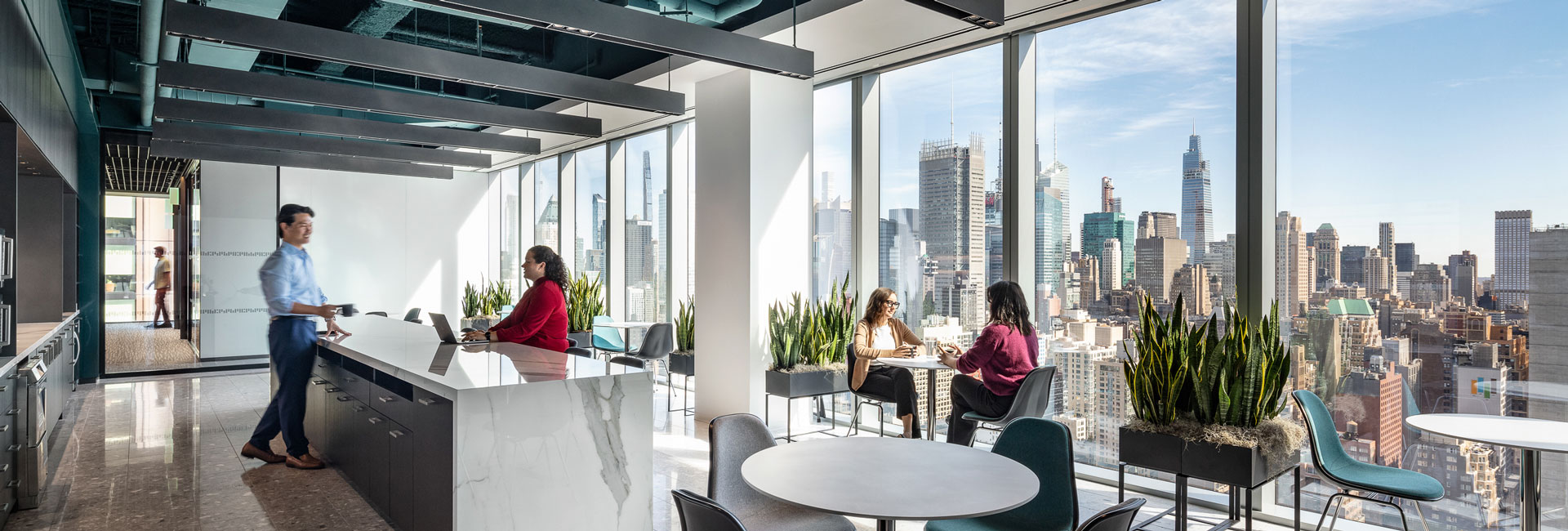 Office scene with individuals at tables, enjoying a panoramic view of the city through expansive glass windows.