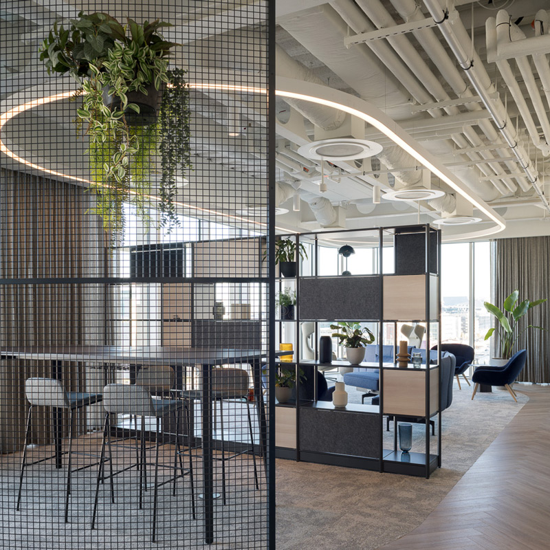 An open office space with tables and chairs for employees to sit and collaborate.