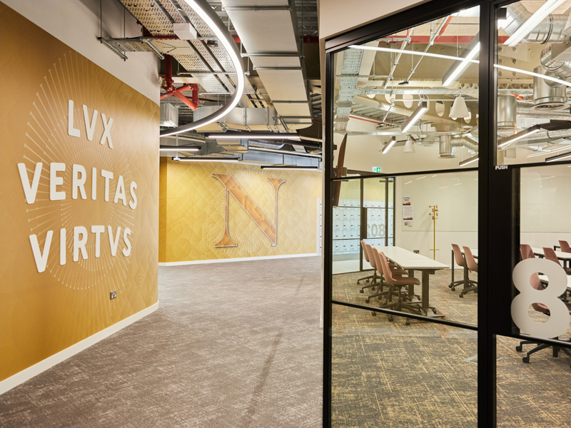 Hallway of Northeastern University with yellow walls and glass doors.